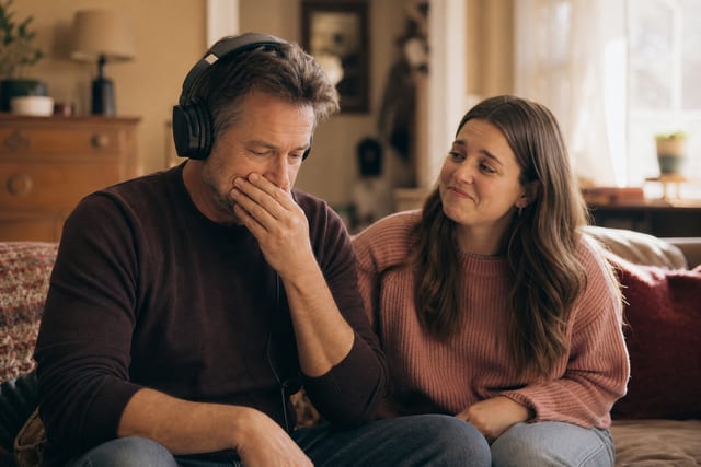 A man listening through headphones while a loved one watches his reaction